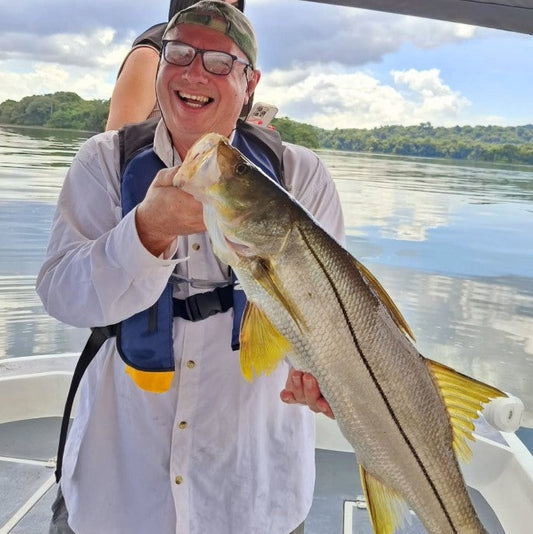 Man holding a large fish on a boat with a scenic background